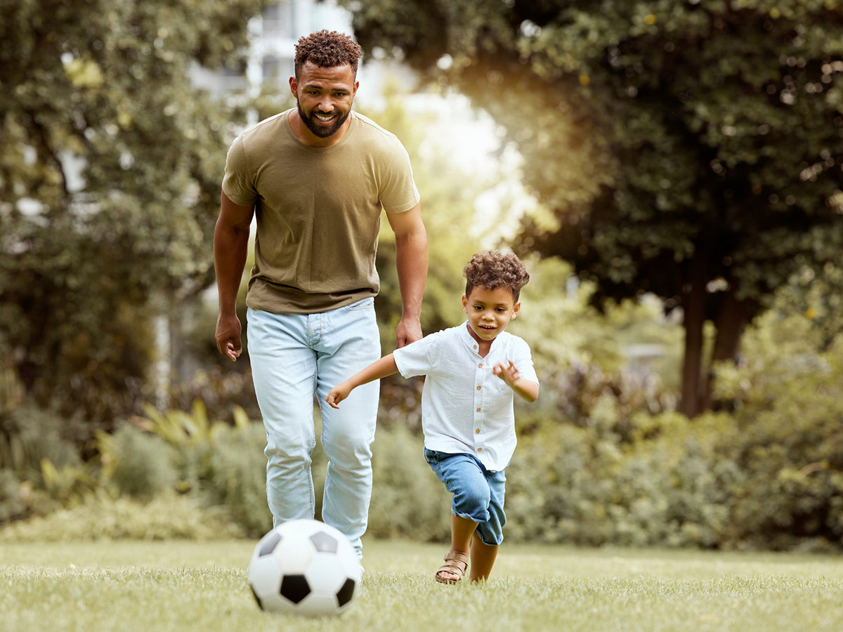 Father and son playing soccer at a park