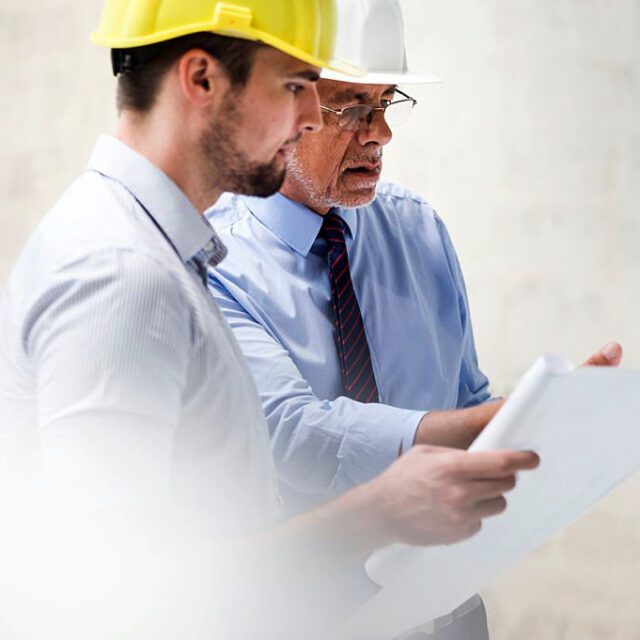 Man Architect And Construction Foreman Looking At Blueprint