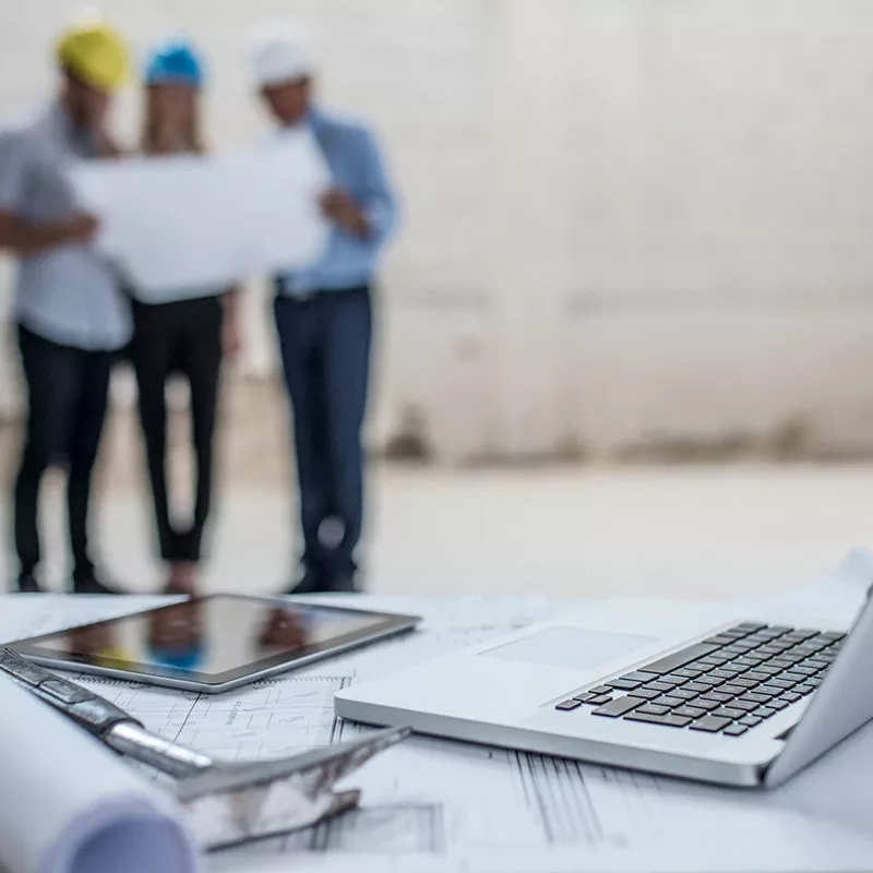Workers In Hard Hats Reviewing Plans