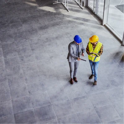 Aeriel View Of Two Men In Hardhats Looking Over Approved Building Plans