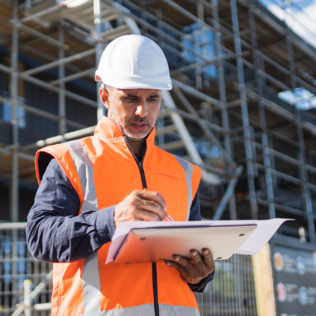 Man Reviewing Papers On Tablet